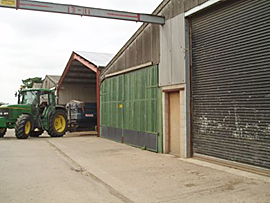 Photo of working farm with Tractor leaving barn.