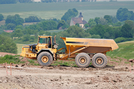 Photo of earth moving vehicle involved in a road building project in a rural setting.